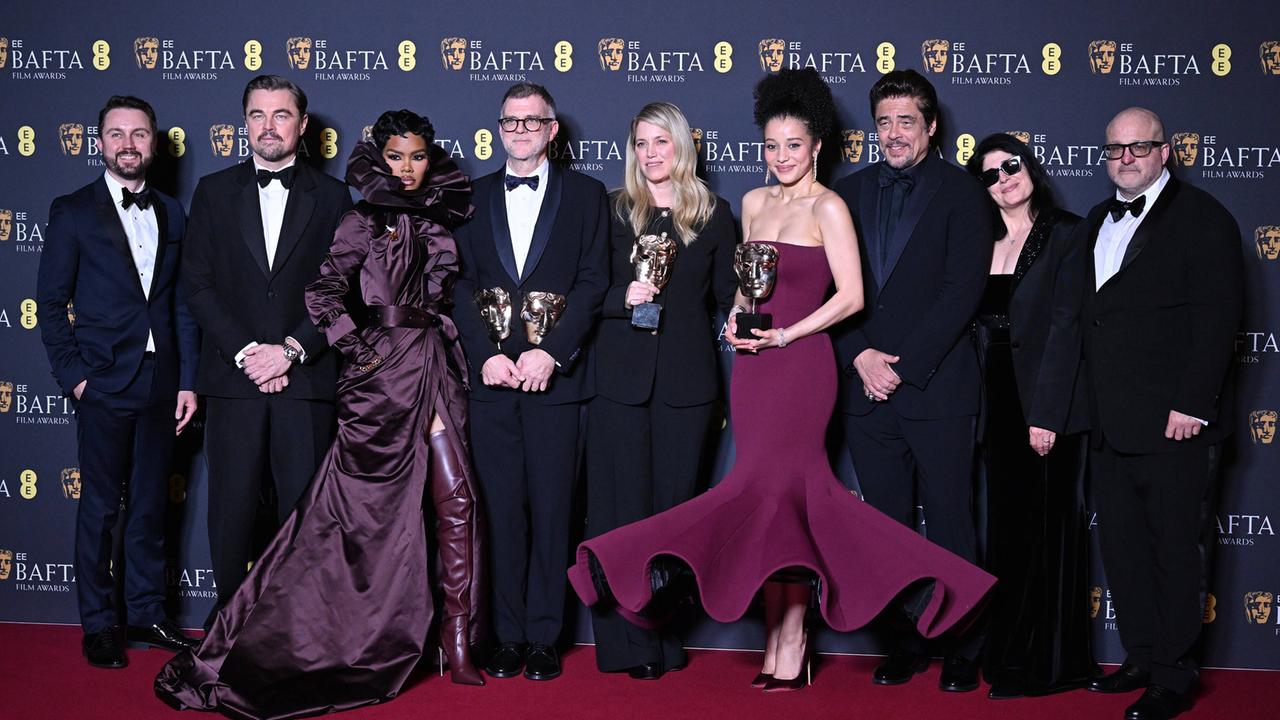 Beteiligte des Films "One Battle After Another" stehen nebeneinander auf dem Roten Teppich und präsentieren Preise.