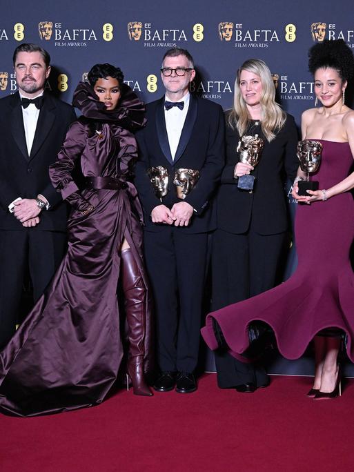 Beteiligte des Films "One Battle After Another" stehen nebeneinander auf dem Roten Teppich und präsentieren Preise.