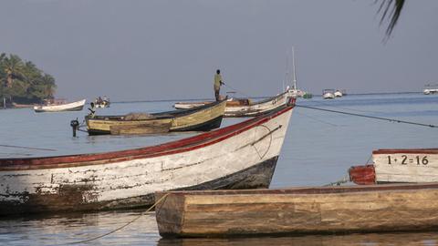 Ein Fischer auf einem Holzboot am Ufer des Malawi-Sees.