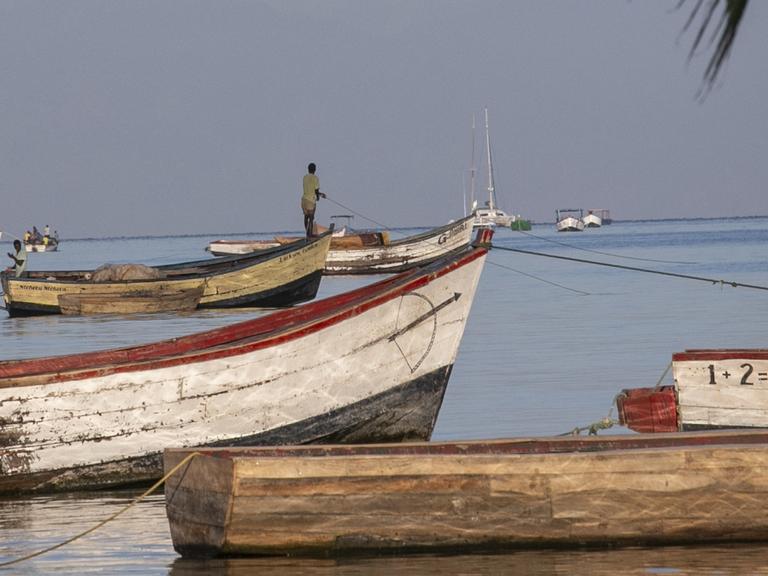 Ein Fischer auf einem Holzboot am Ufer des Malawi-Sees.