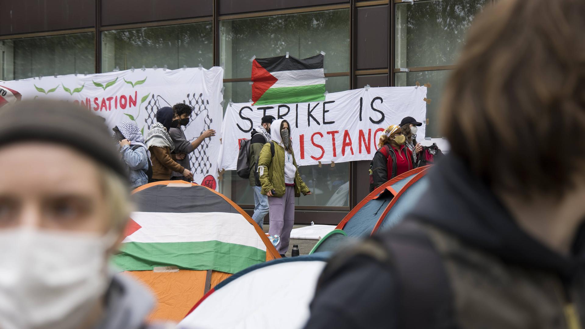 Pro-Palästina-Protestcamp an der FU Berlin. Eine Palästina-Fahne liegt auf einem Zelt, eine hängt an einer Wand.