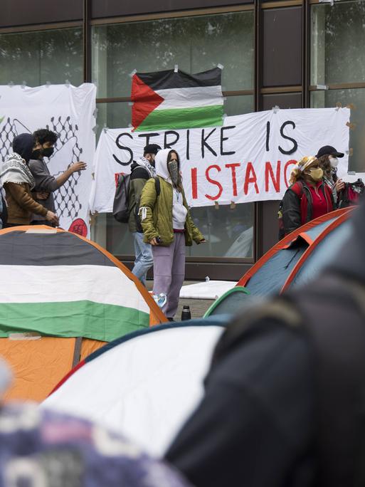 Pro-Palästina-Protestcamp an der FU Berlin. Eine Palästina-Fahne liegt auf einem Zelt, eine hängt an einer Wand.