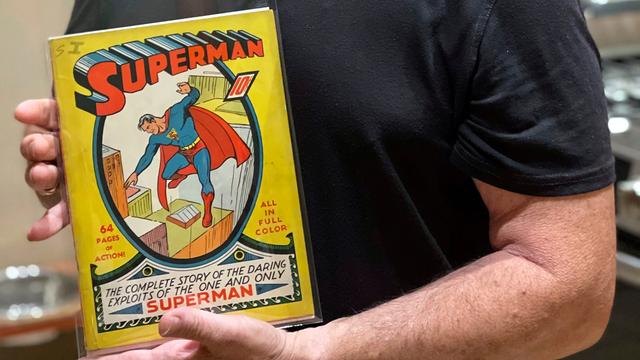 Auf der Titelseite steht oben groß Superman in rot. Darunter ist Superman zu sehen, der über den Dächern von Hoch-Häusern in der Luft steht. Der Hintergrund ist gelb.