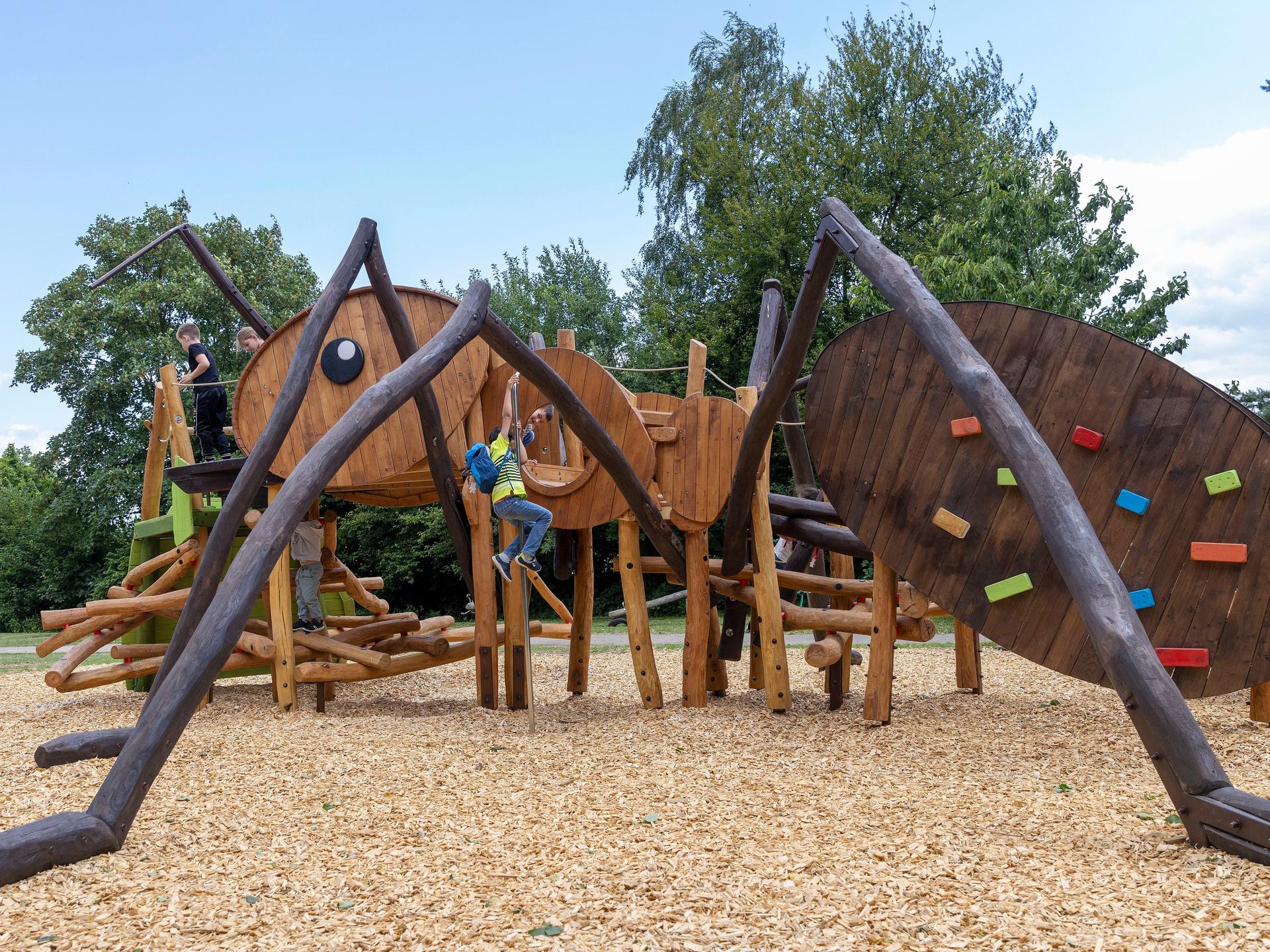 Kinder klettern auf einem Holzgerüst in Form einer Ameise.