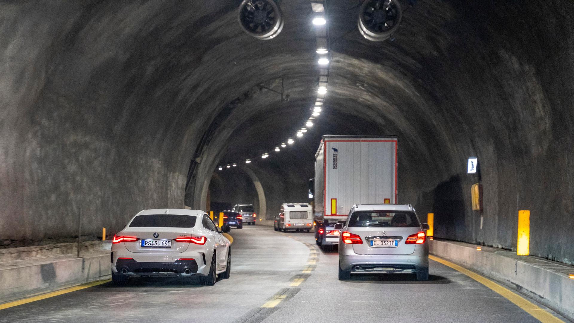 Fahrzeuge fahren durch einen dunklen Tunnel auf einer Autobahn in Italien. 