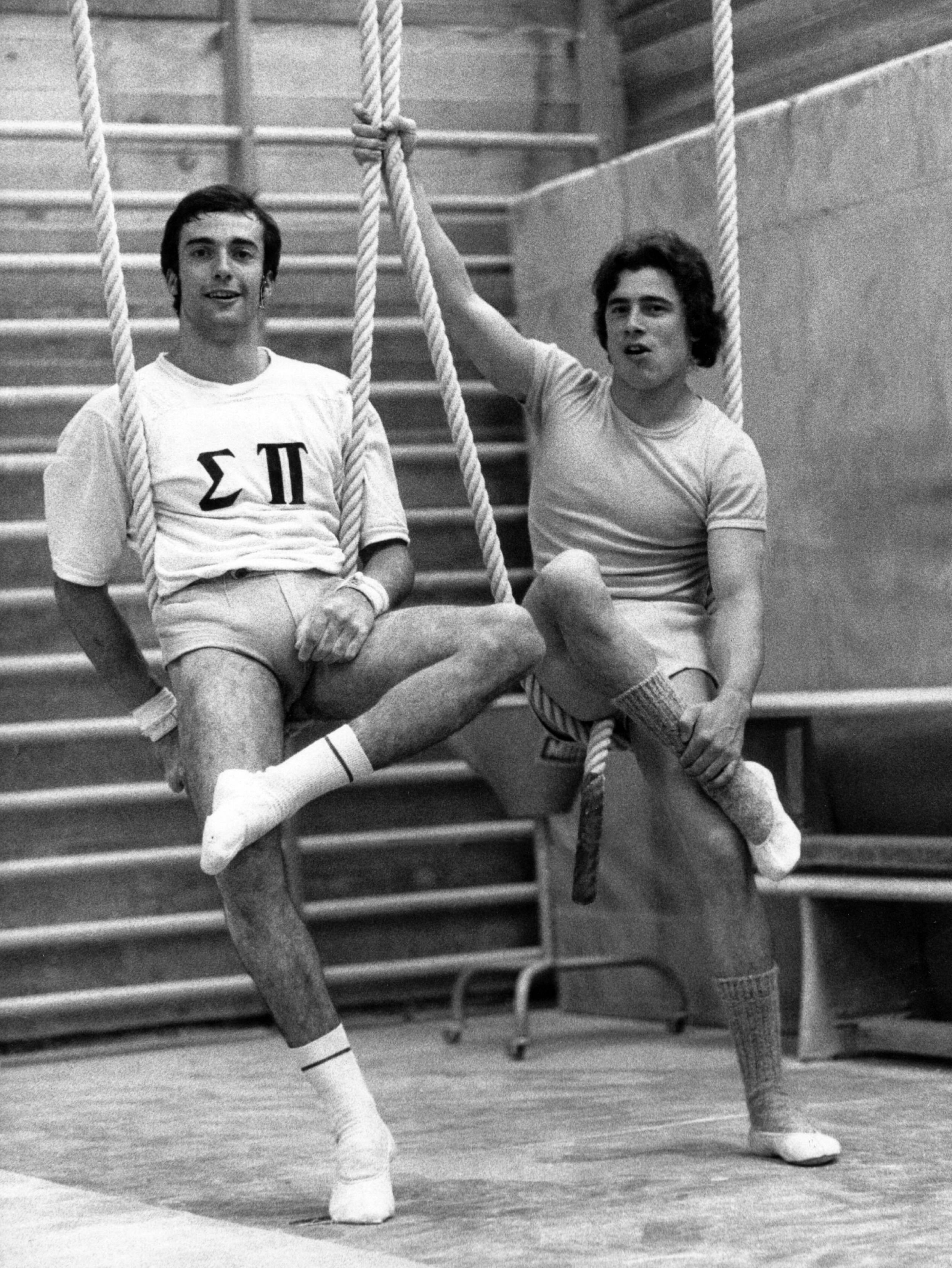 Eberhard Gienger (links, BRD) und Wolfgang Thüne (rechts, DDR) nebeneinander auf einem Turngerät, beide lächeln.