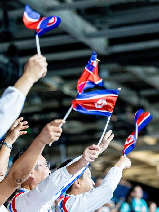 Nordkoreanische Fans winken Fahnen bei den Olympischen Spielen in Paris im Tischtennis.  