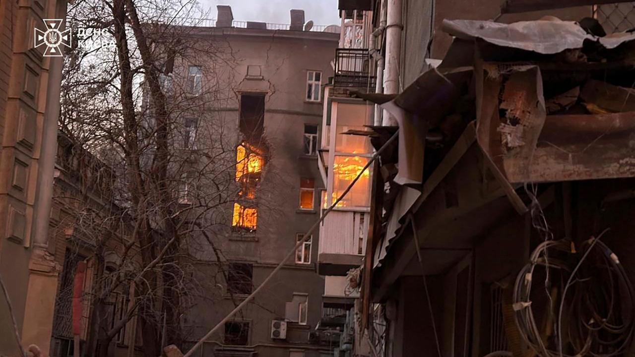 Auf dem Bild ist ein Wohnhaus in Kiew. Aus mehrere Fenstern schlagen Flammen. 