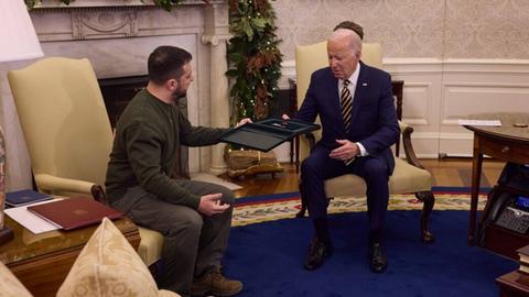 Der ukrainische Präsident Selenskyj übergibt US-Präsident Biden vor einem Kamin im Weißen Haus in Washington einen Orden.