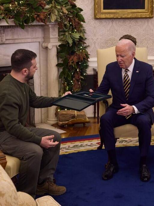 Der ukrainische Präsident Selenskyj übergibt US-Präsident Biden vor einem Kamin im Weißen Haus in Washington einen Orden.