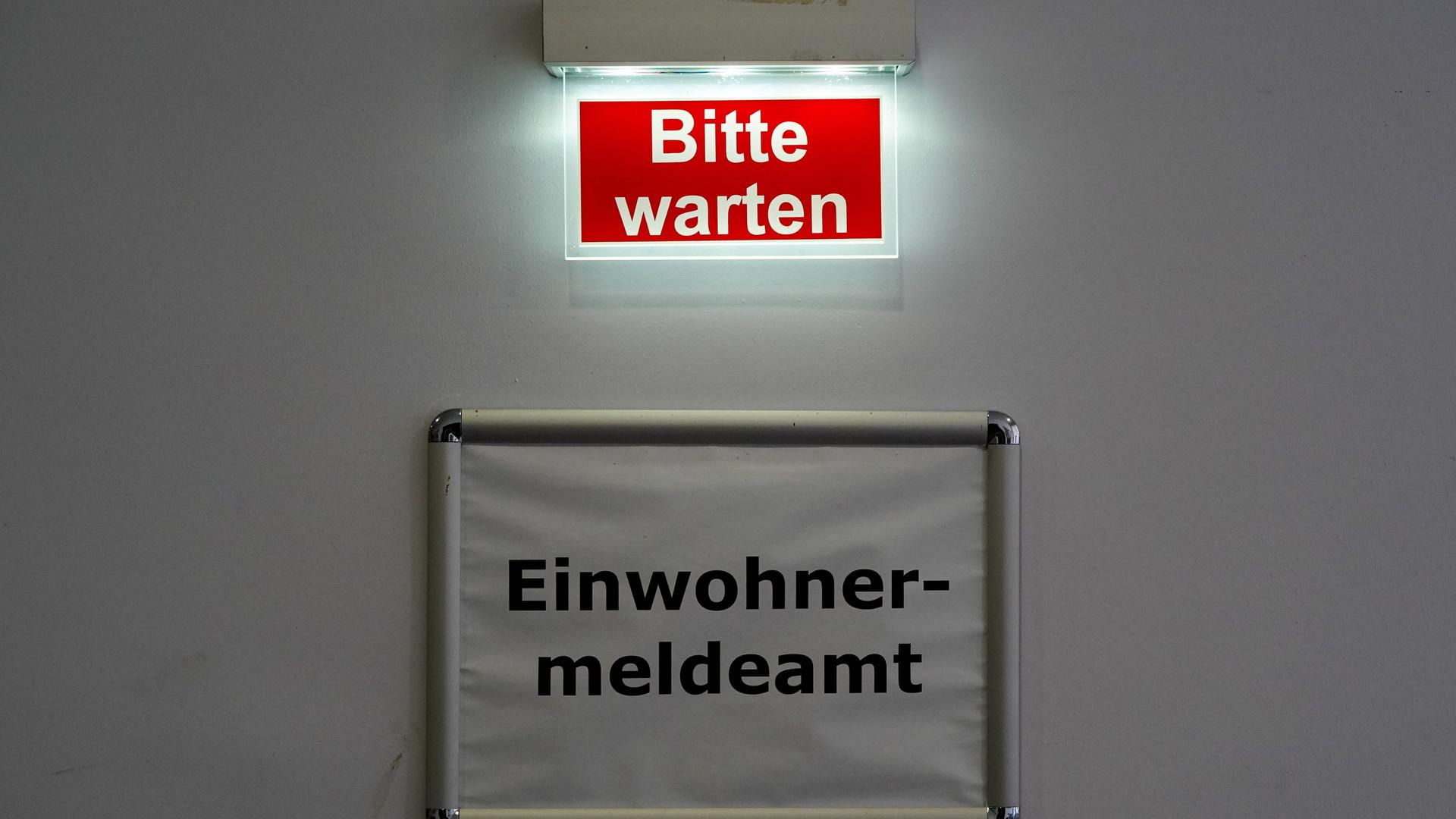 Der Schriftzug Bitte warten steht über dem Schild des Behördenbereichs Einwohnermeldeamt. Markkleeberg, Sachsen, Deutschland