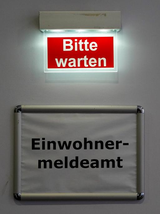 Der Schriftzug Bitte warten steht über dem Schild des Behördenbereichs Einwohnermeldeamt. Markkleeberg, Sachsen, Deutschland