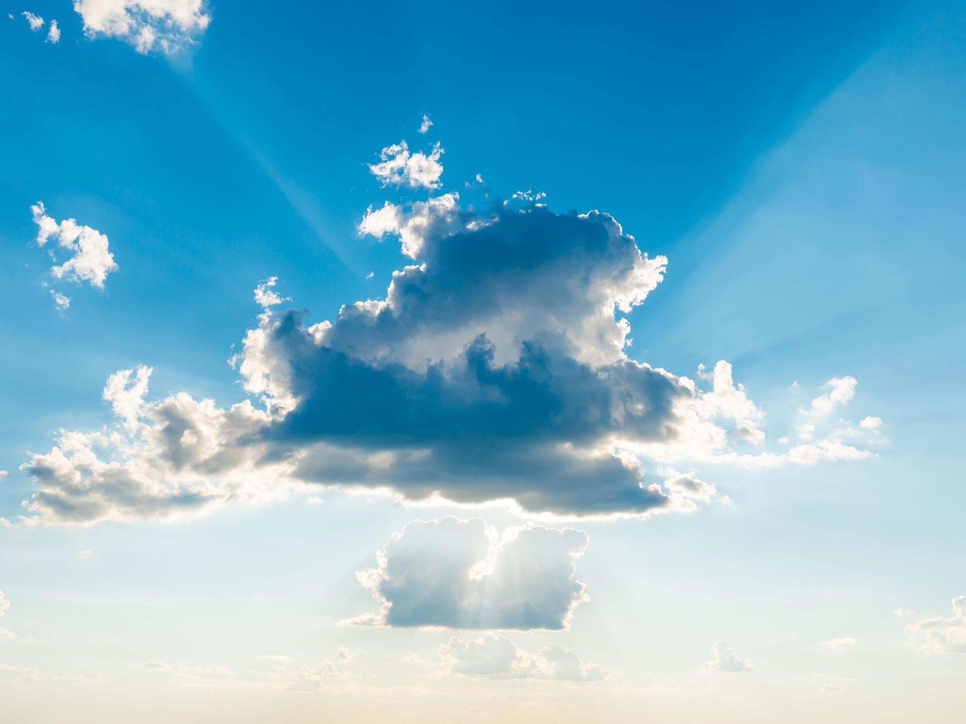Sonnenlicht bricht durch die Wolken am blauen Himmel.