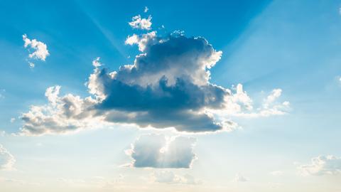Sonnenlicht bricht durch die Wolken am blauen Himmel.