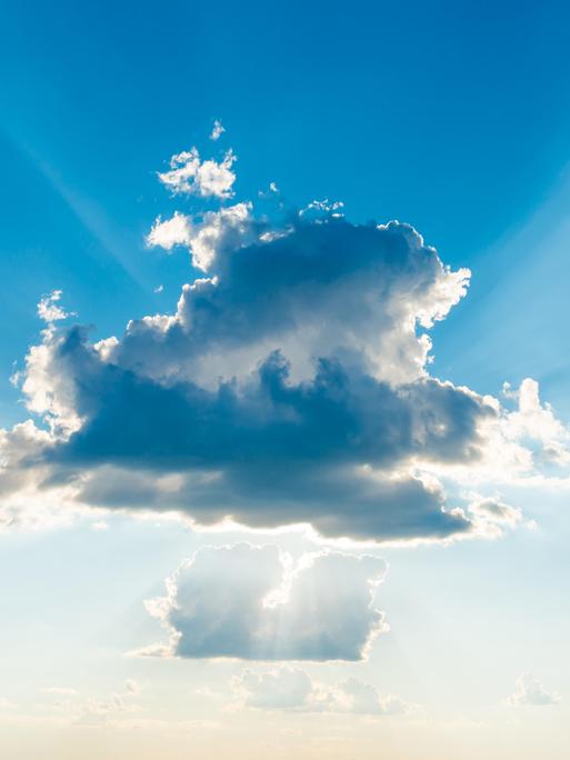 Sonnenlicht bricht durch die Wolken am blauen Himmel.