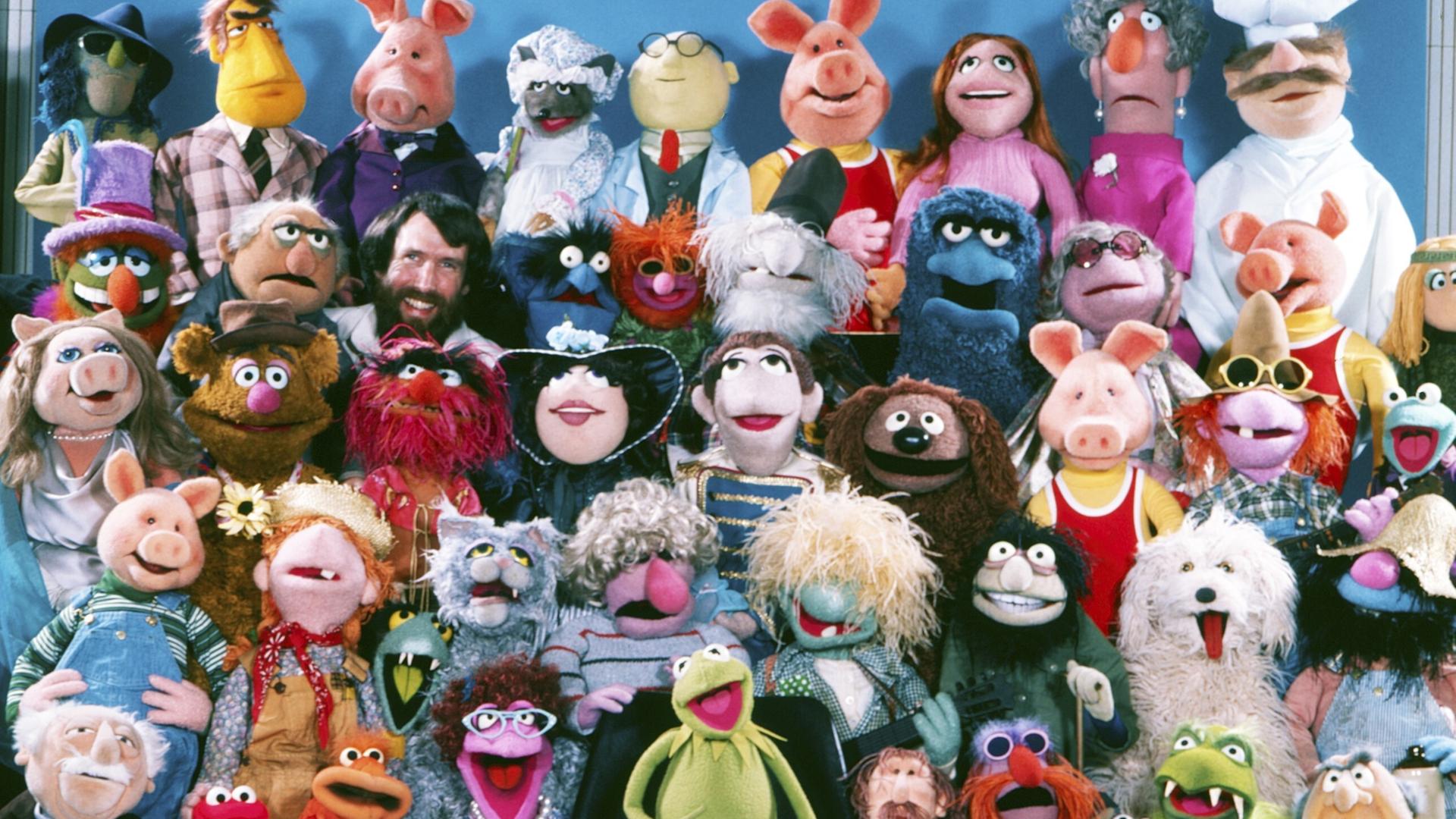 Puppengruppenbild der Muppet-Show mit (neben vielen anderen) Miss Piggy, Kermit, dem schwedischen Koch, Fozzybär und natürlich dem Muppets-Erfinder Jim Henson