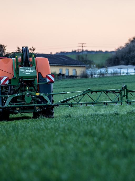 Ein Landwirt bringt mit seinem Traktor ein Pflanzenschutzmittel auf einem Feld aus. 