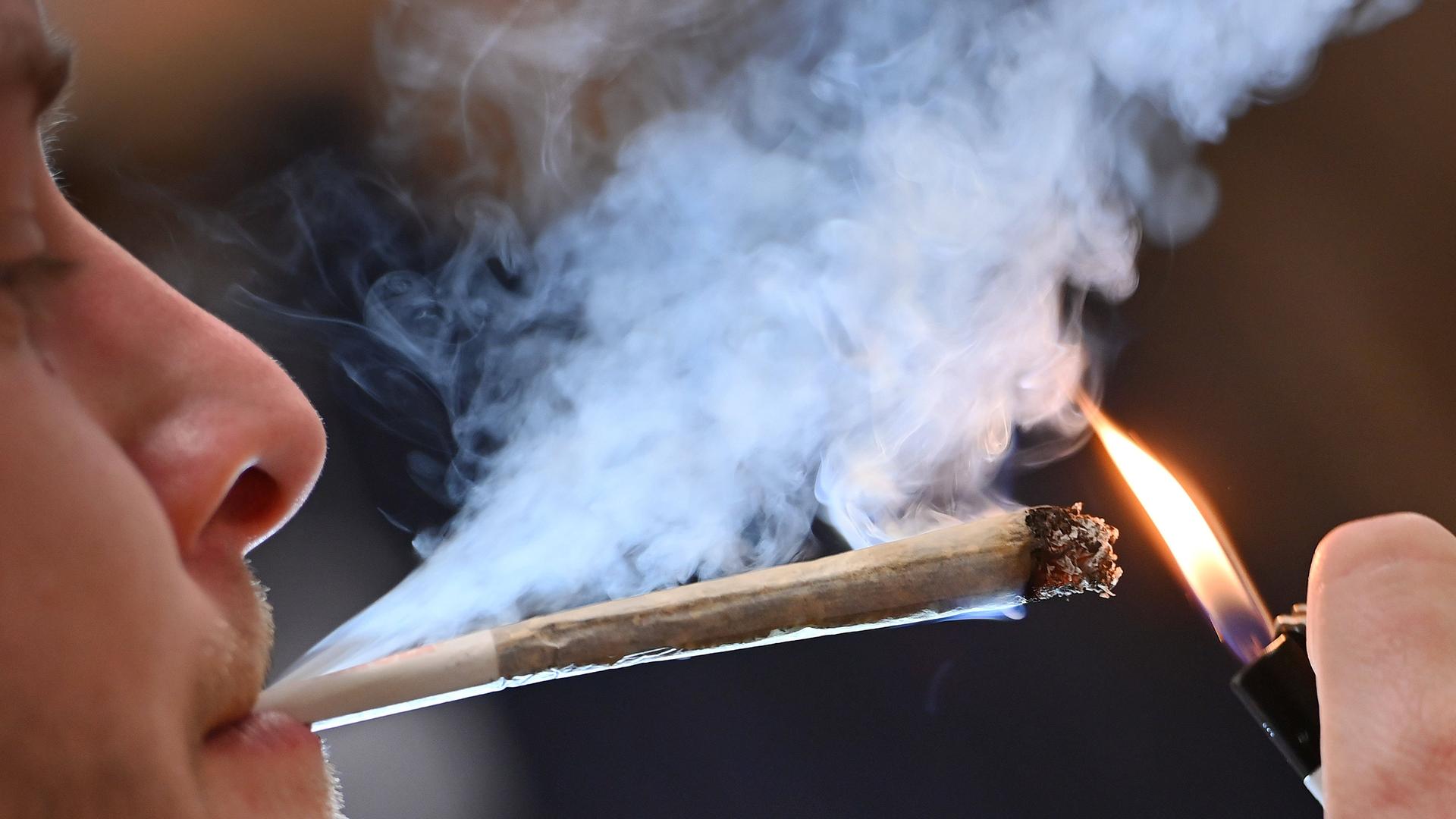 Ein Mann zündet sich eine Cannabis-Zigarette an.