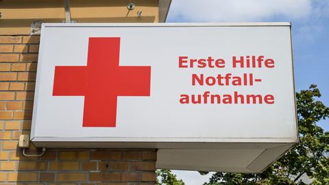 Auf einem Schild sind neben einem roten Kreuz die Worte "Erste Hilfe, Notaufnahme" zu lesen.