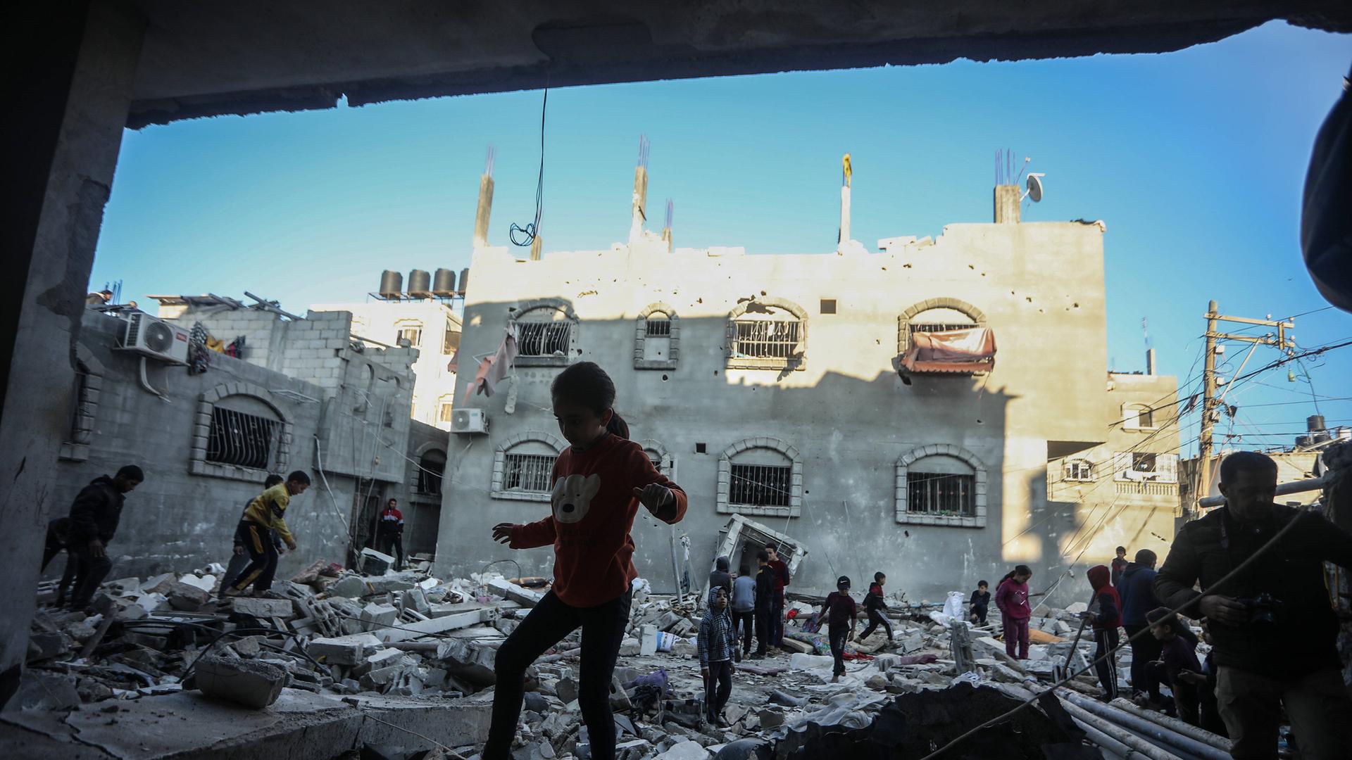 Menschen laufen über Trümmer von Häusern in Rafah im Gazastreifen