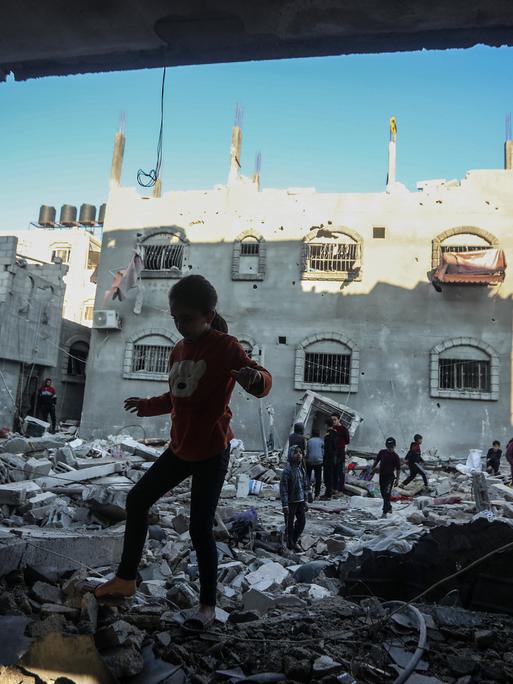 Menschen laufen über Trümmer von Häusern in Rafah im Gazastreifen