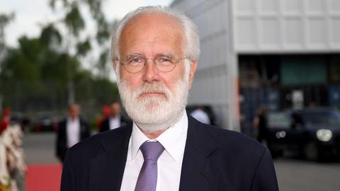 Harald Schmidt steht im Freien. Er trägt einen weißen Bart und Krawatte. Er blickt in die Kamera.
