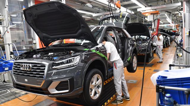 Zwei Mitarbeiter montieren bei Audi "just in sequence" die beiden Vordersitze eines Autos mithilfe eines ergonomischen Handlingsgeraets an der Karosserie.