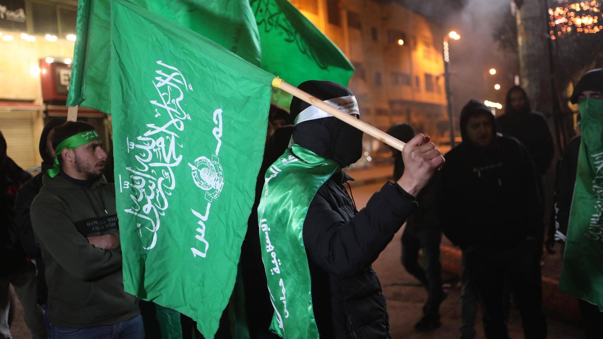 Ein Hamas-Anhänger schwenkt eine grüne Fahne bei einer Demonstration in Hebron nach dem Tod von Hamas-Führer Saleh al-Aruri.