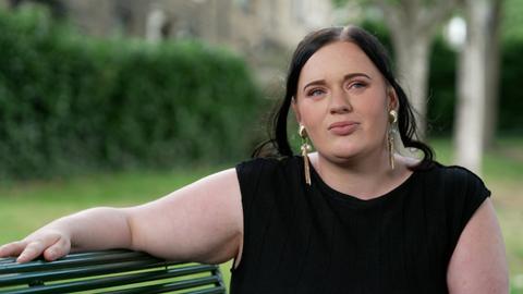 Fiona Goddard sitzt auf einer Bank und schaut zur Seite