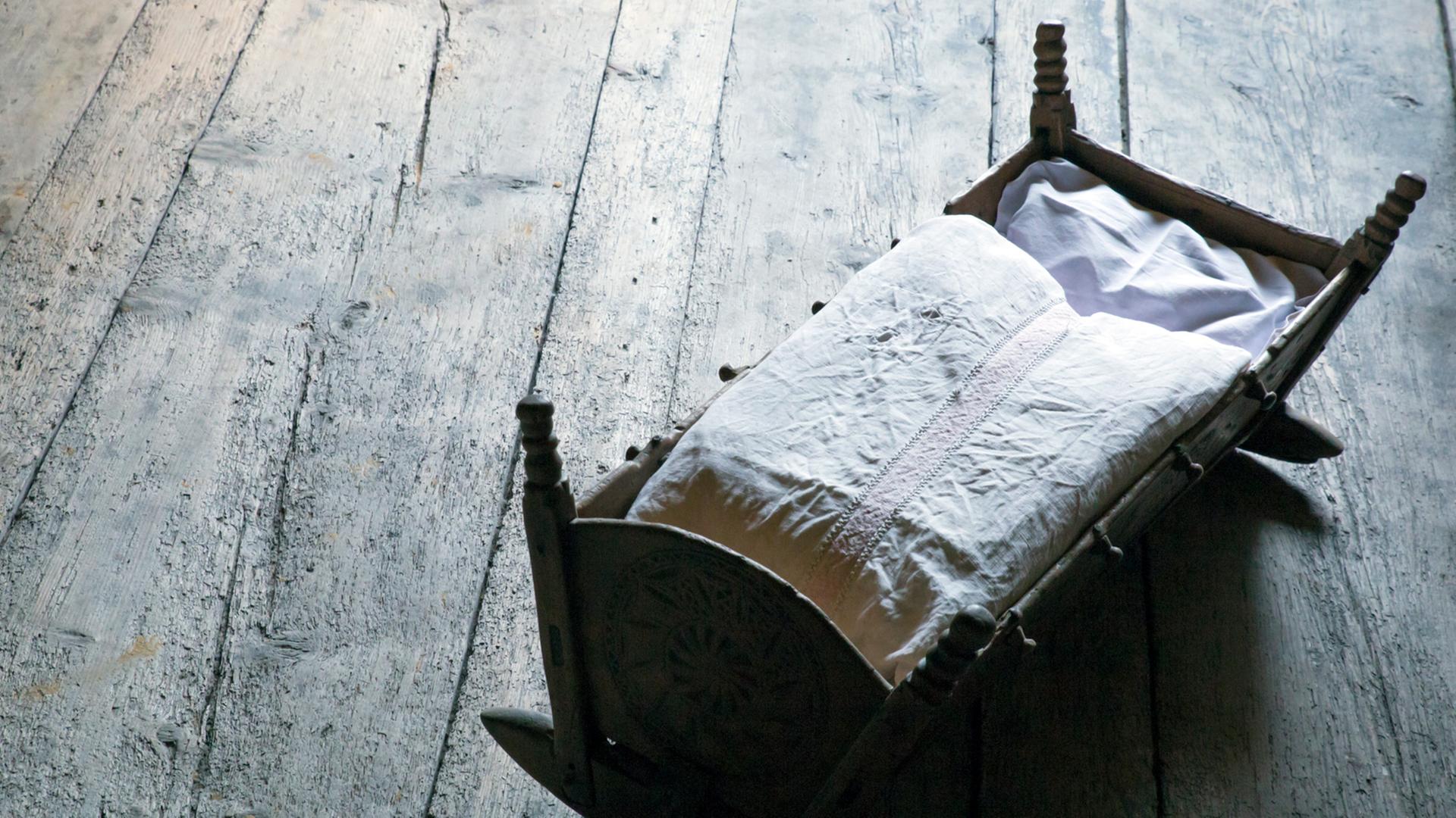 Annegret Krauser hat vor ihrem Tod entbunden. Wo ist das Kind? Zu sehen: Ein Kinderbett auf einem grauen Holzboden. 