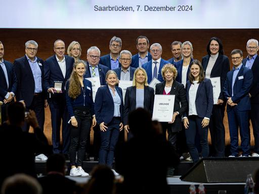 Die Teilnehmerinnen und Teilnehmer der 21. Mitgliederversammlung des DOSB stehen zu einem Fotoshooting zusammen.