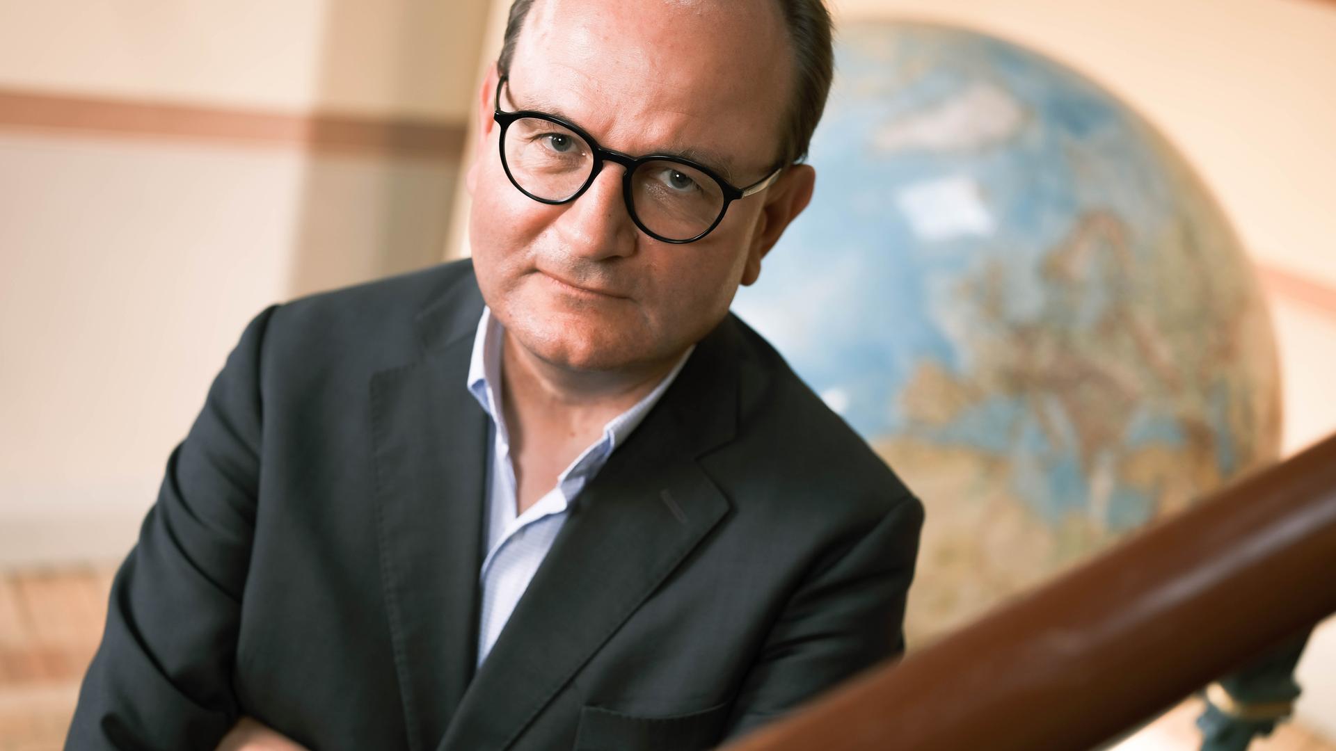 Prof. Ottmar Edenhofer vom Potsdam-Institut für Klimafolgenforschung am 17. August 2022 in den Räumen des PIK, mit einem großen Globus im Hintergrund