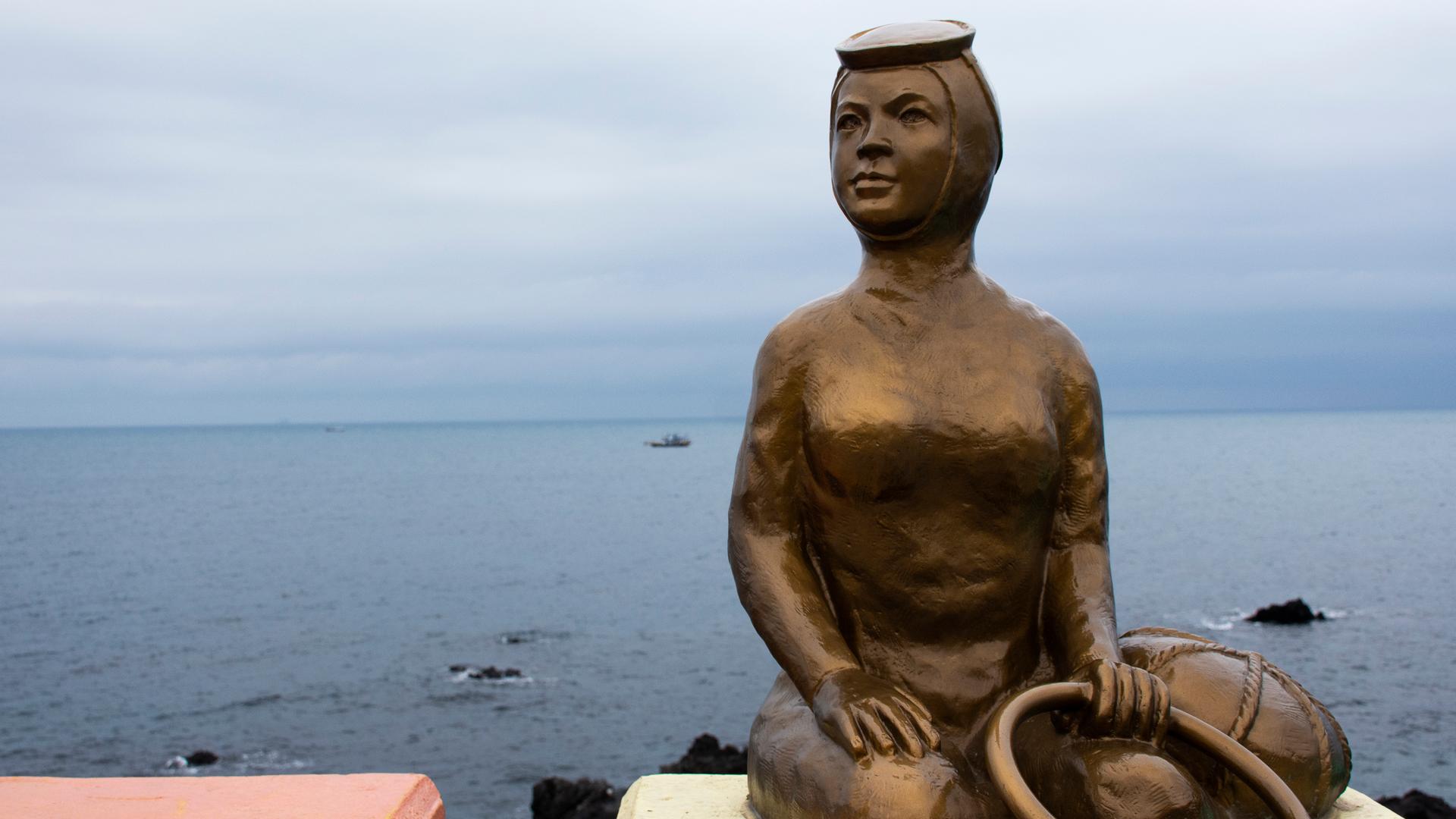 Eine Statue zeigt eine Frau mit Tauchermaske zu Ehren der berühmten Haenyo-Taucherinnen Eine Statue zeigt eine Frau mit Tauchermaske zu Ehren der berühmten Haenyo-Taucherinnen