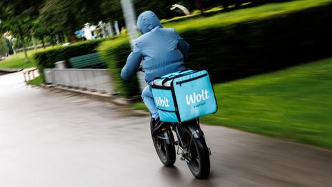 Ein Wolt-Fahrradkurier fährt durch einen Park