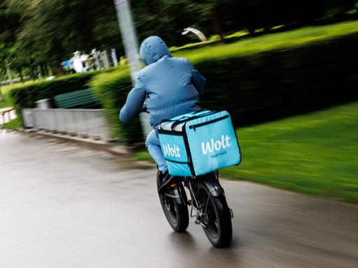 Ein Wolt-Fahrradkurier fährt durch einen Park