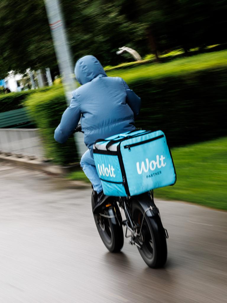 Ein Wolt-Fahrradkurier fährt durch einen Park