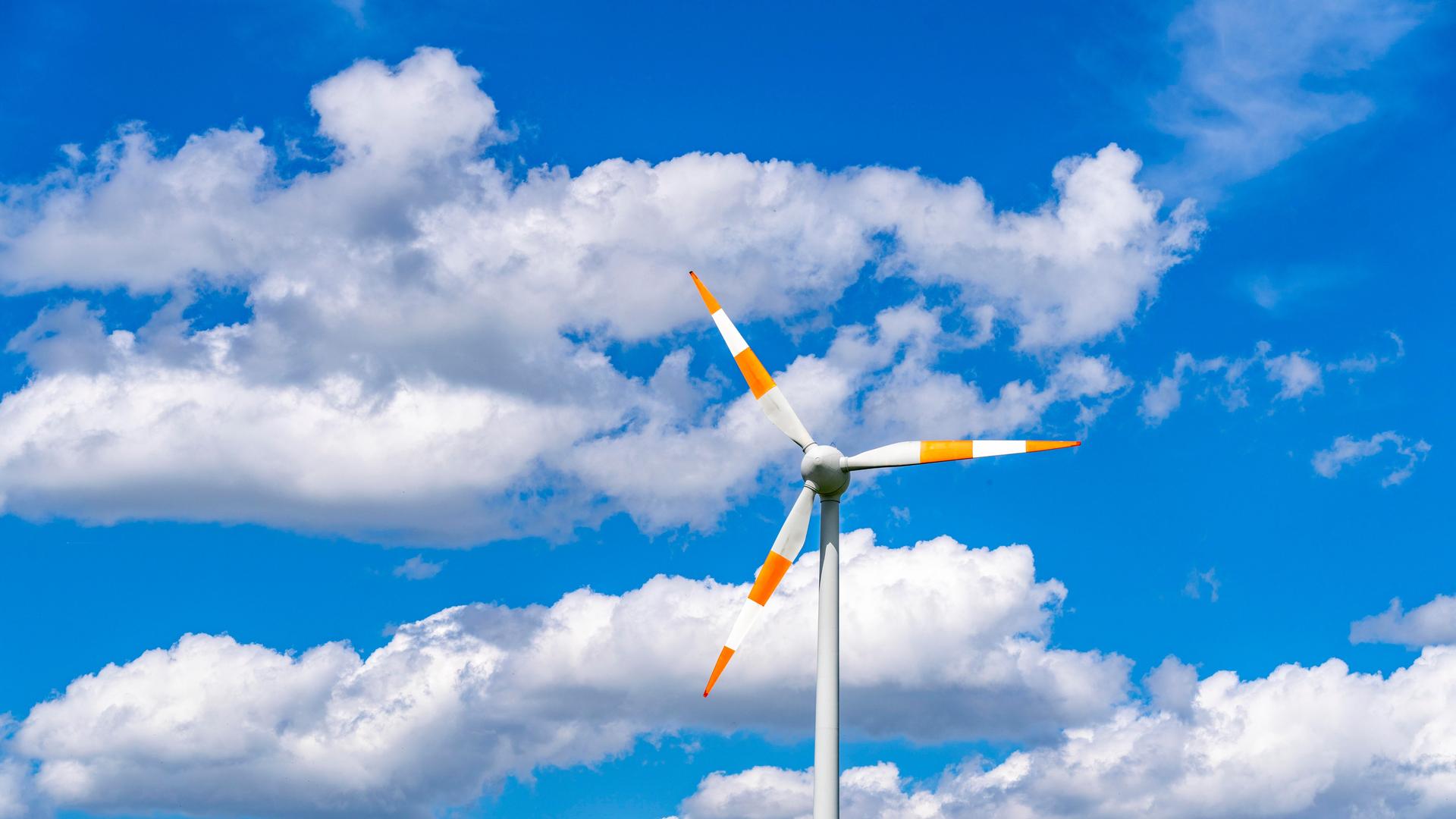 Windrad einer Winenergieanlage vor blauem Himmel mit vielen weißen Wolken.