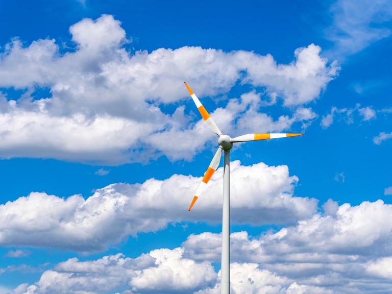 Windrad einer Winenergieanlage vor blauem Himmel mit vielen weißen Wolken.