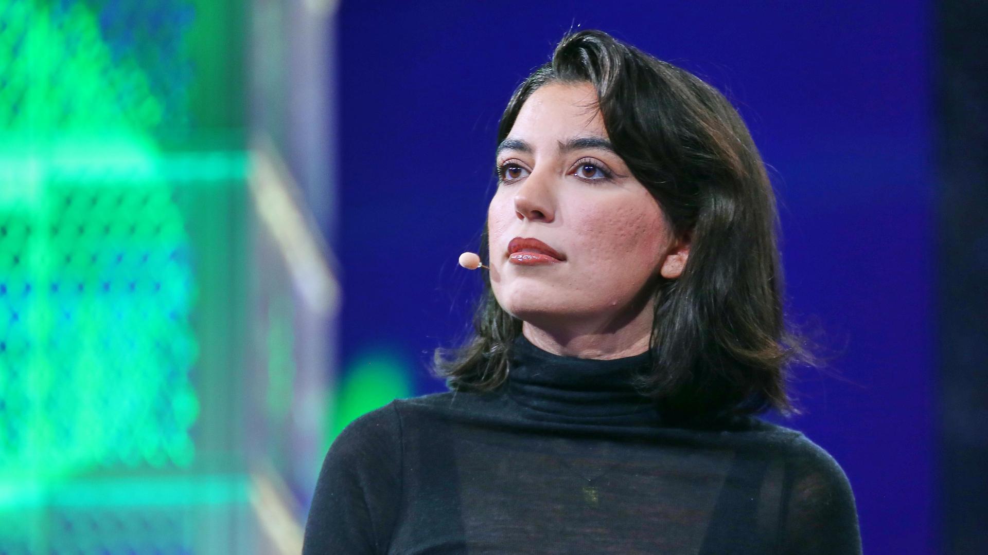 Eine Frau mit schwarzen Haaren steht auf der Bühne und schaut in das Publikum. Eine Frau mit schwarzen Haaren steht auf der Bühne und schaut in das Publikum.