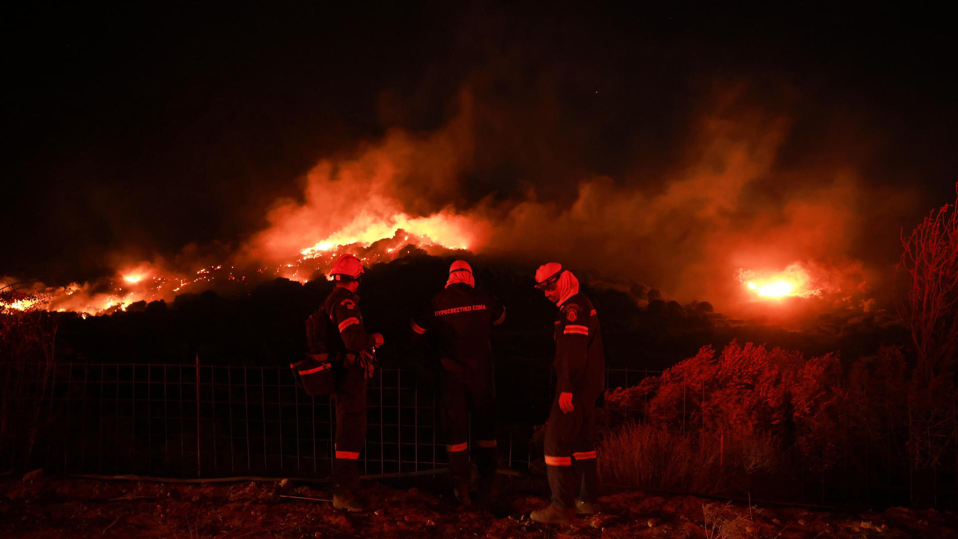 Feuerwehrleute stehen nachts vor Flammen eines Waldbrandes in der Nähe des Dorfes Preveli auf der griechischen Insel Kreta. Feuerwehrleute stehen nachts vor Flammen eines Waldbrandes in der Nähe des Dorfes Preveli auf der griechischen Insel Kreta.