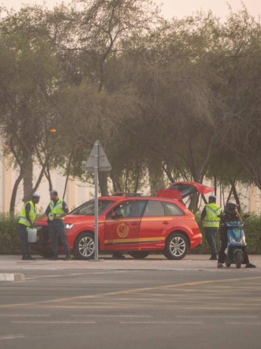 Sicherheitspersonal mit zwei roten Autos stehen in der Nähe des Anschlags in Doha.