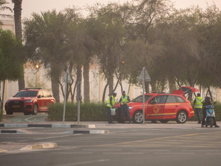 Sicherheitspersonal mit zwei roten Autos stehen in der Nähe des Anschlags in Doha.