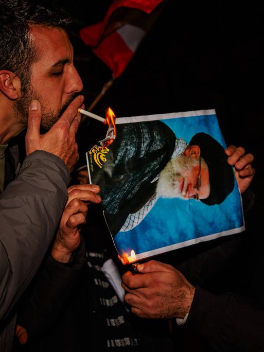 Bei Protesten in London, Großbritannien, zündet ein Mann mit einer Zigarette ein Bildnis des iranischen Revolutionsführers an (12. Januar 2026)