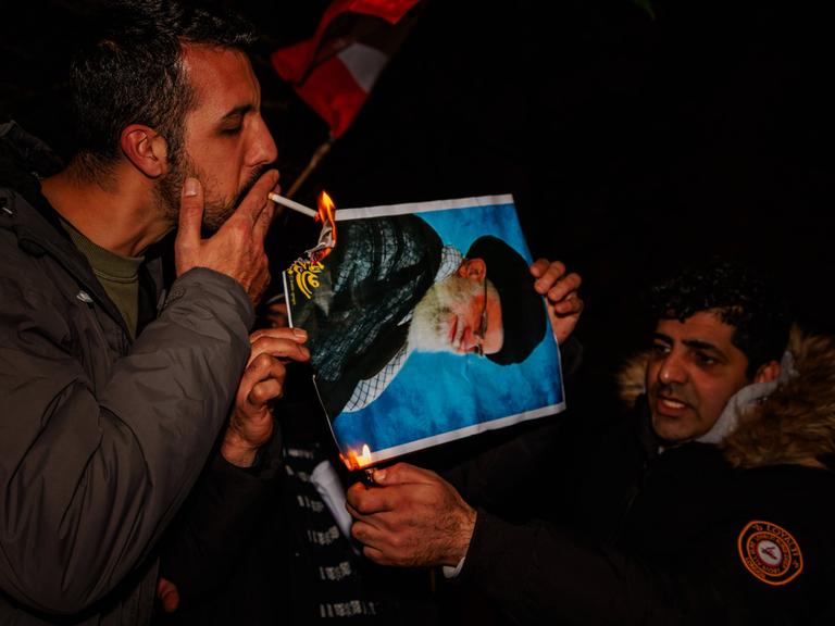 Bei Protesten in London, Großbritannien, zündet ein Mann mit einer Zigarette ein Bildnis des iranischen Revolutionsführers an (12. Januar 2026)