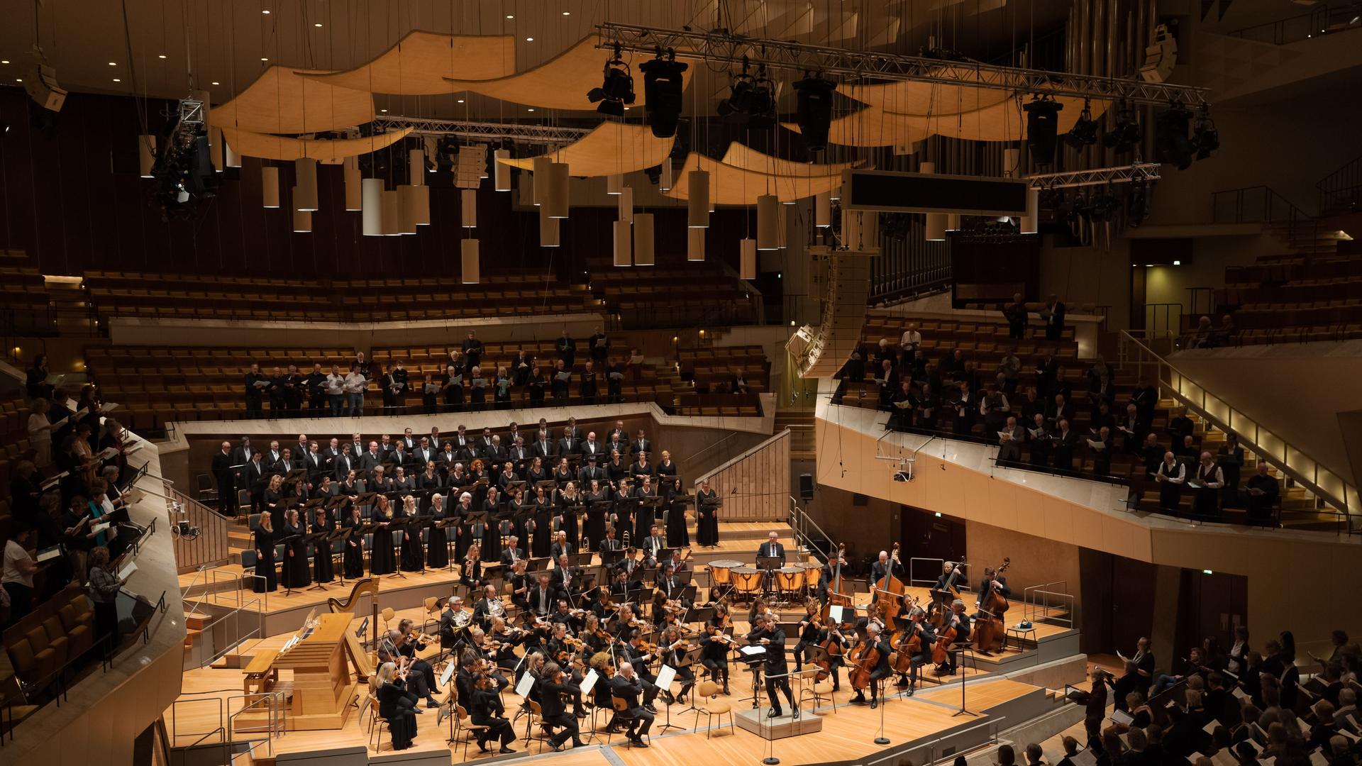 Ein Chor und ein Orchester sind auf der Bühne der vollbesetzten Philharmonie Berlin