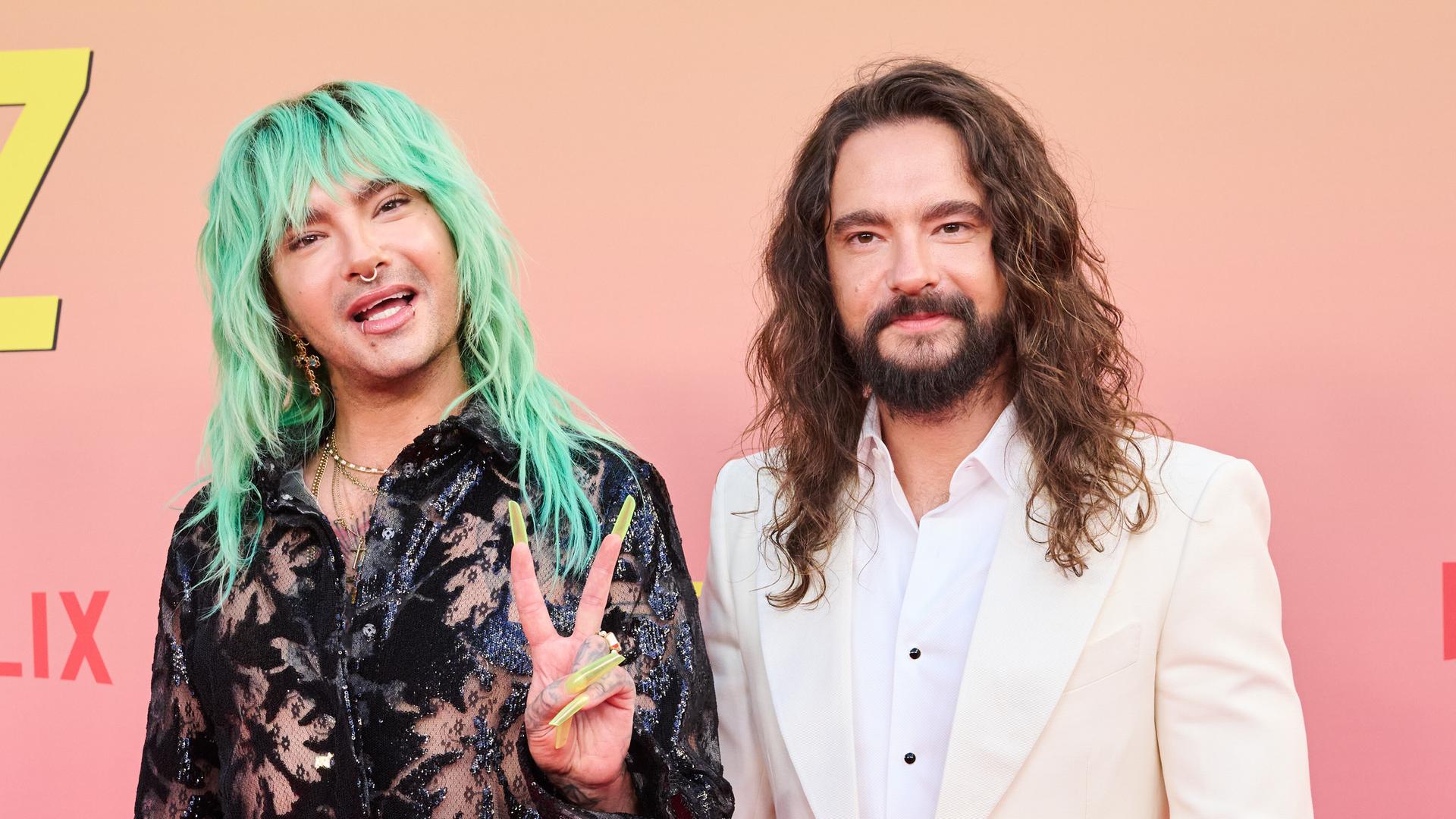 Die Brüder Bill (links) und Tom Kaulitz auf dem roten Teppich des Delphi-Filmpalasts in Berlin. Bill hat grüne, lange Haare und zeigt das Peace-Zeichen. 