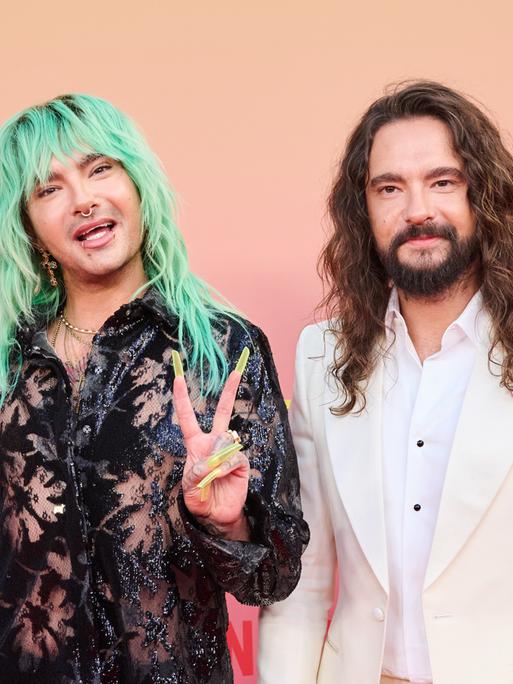 Die Brüder Bill (links) und Tom Kaulitz auf dem roten Teppich des Delphi-Filmpalasts in Berlin. Bill hat grüne, lange Haare und zeigt das Peace-Zeichen. 