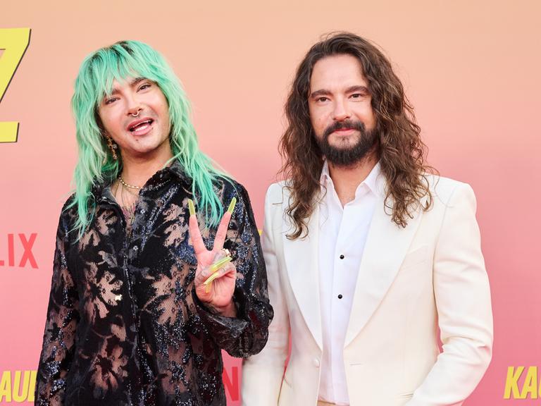 Die Brüder Bill (links) und Tom Kaulitz auf dem roten Teppich des Delphi-Filmpalasts in Berlin. Bill hat grüne, lange Haare und zeigt das Peace-Zeichen. 