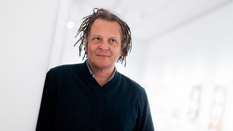 Porträt von Martin Schoeller. Er trägt einen dunkelblauen Pulli und kinnlange Dreadlocks.