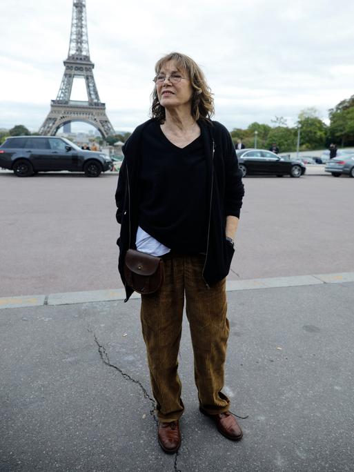 Jane Birkin steht im Oktober 2017 vor dem Eiffelturm. Sie trägt eine braune Kordhose und einen schwarzen Pulli im Oversized-Look.